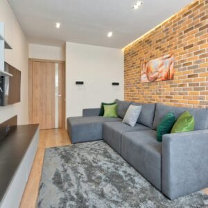 Stylish living room featuring a gray L-shaped sofa, brick wall, and modern decor.